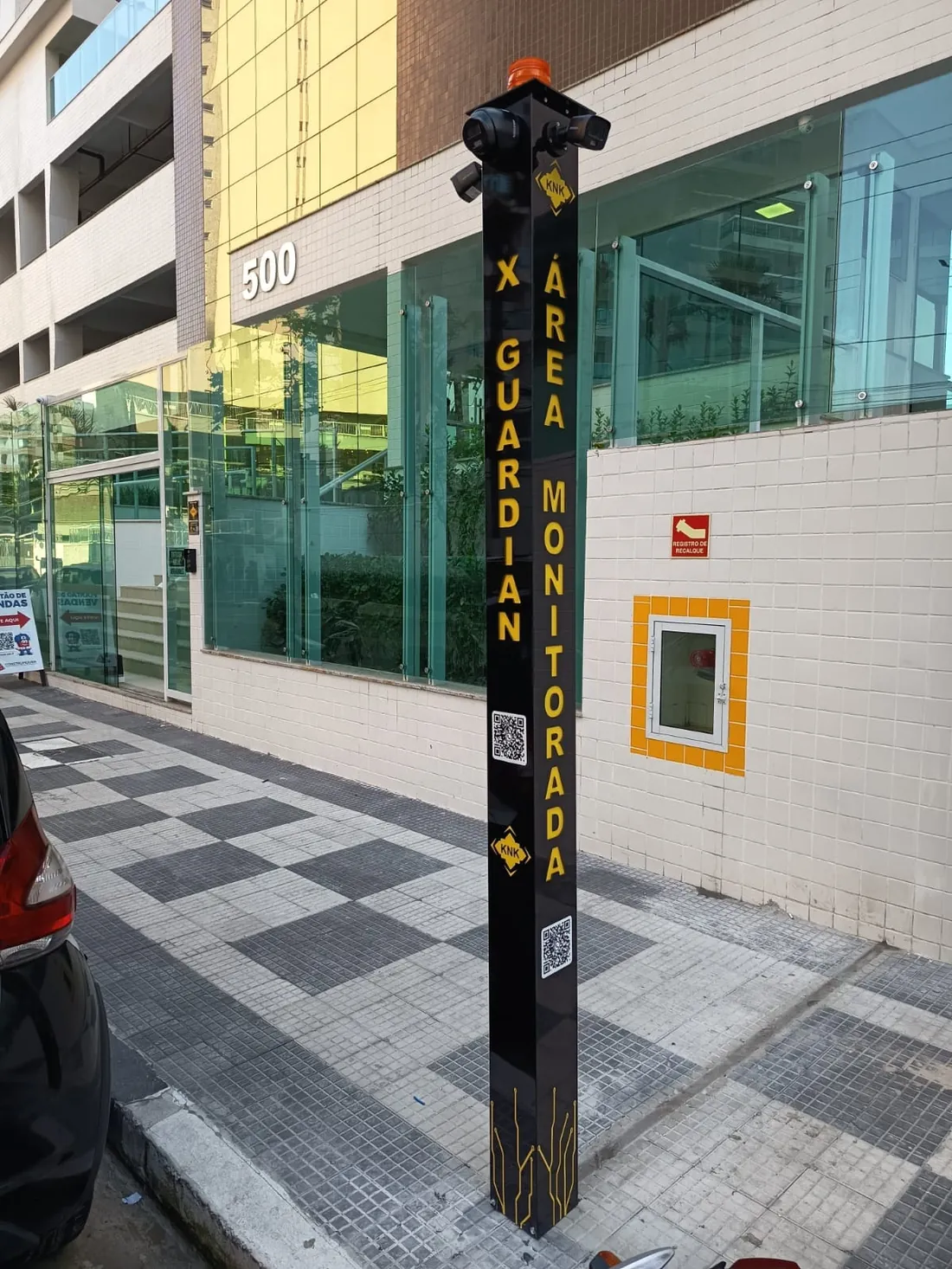 Torre XGUARDIAN instalada na calçada, com câmeras no topo e sinalização de área monitorada